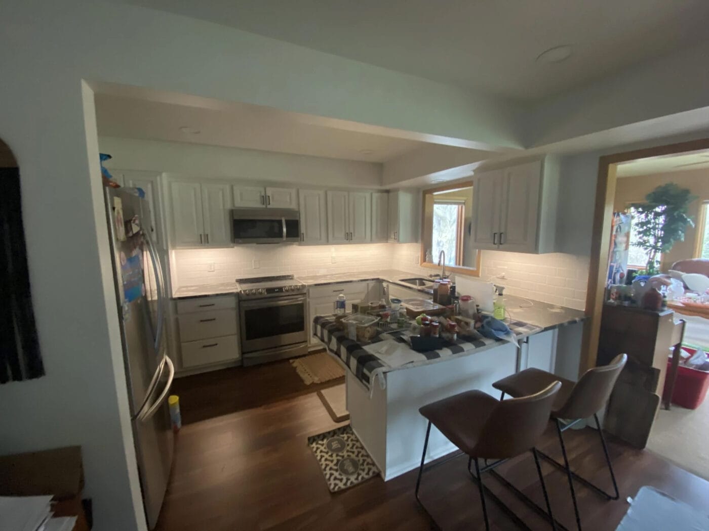 A modern kitchen with white cabinetry, stainless steel appliances, and a center island covered in various items.