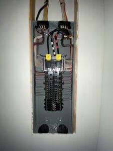 Electrical panel with multiple circuit breakers and wiring neatly organized.